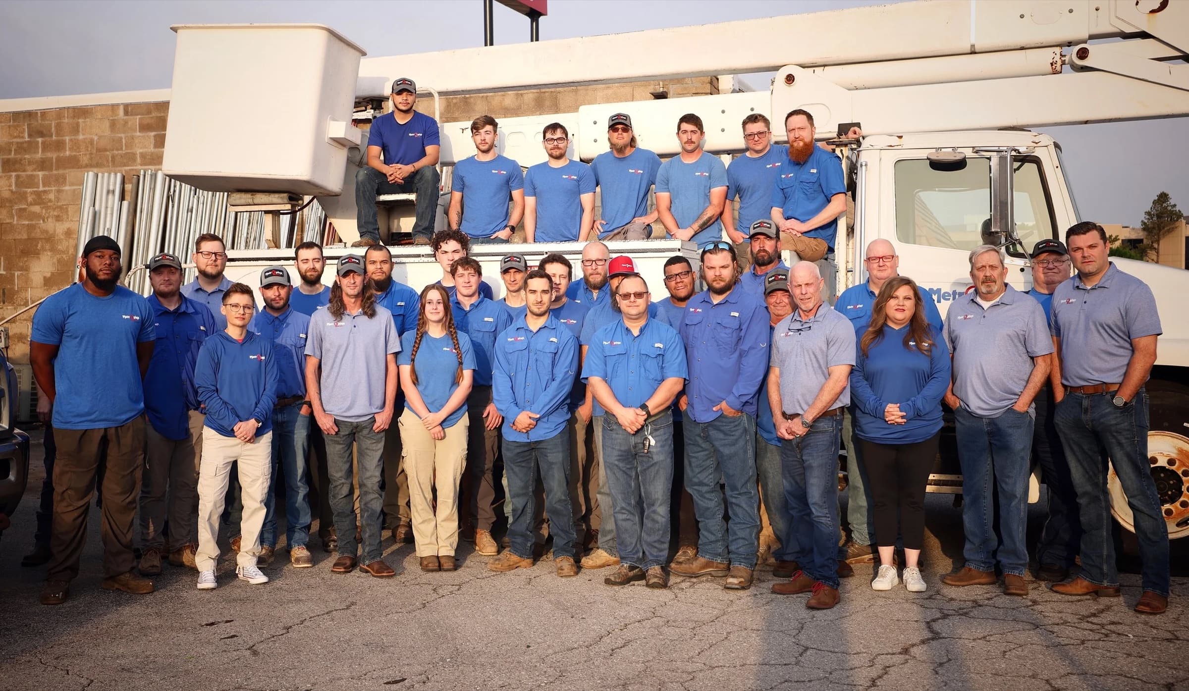 The Metroplex crew in matching blue shirts in front of a bucket truck